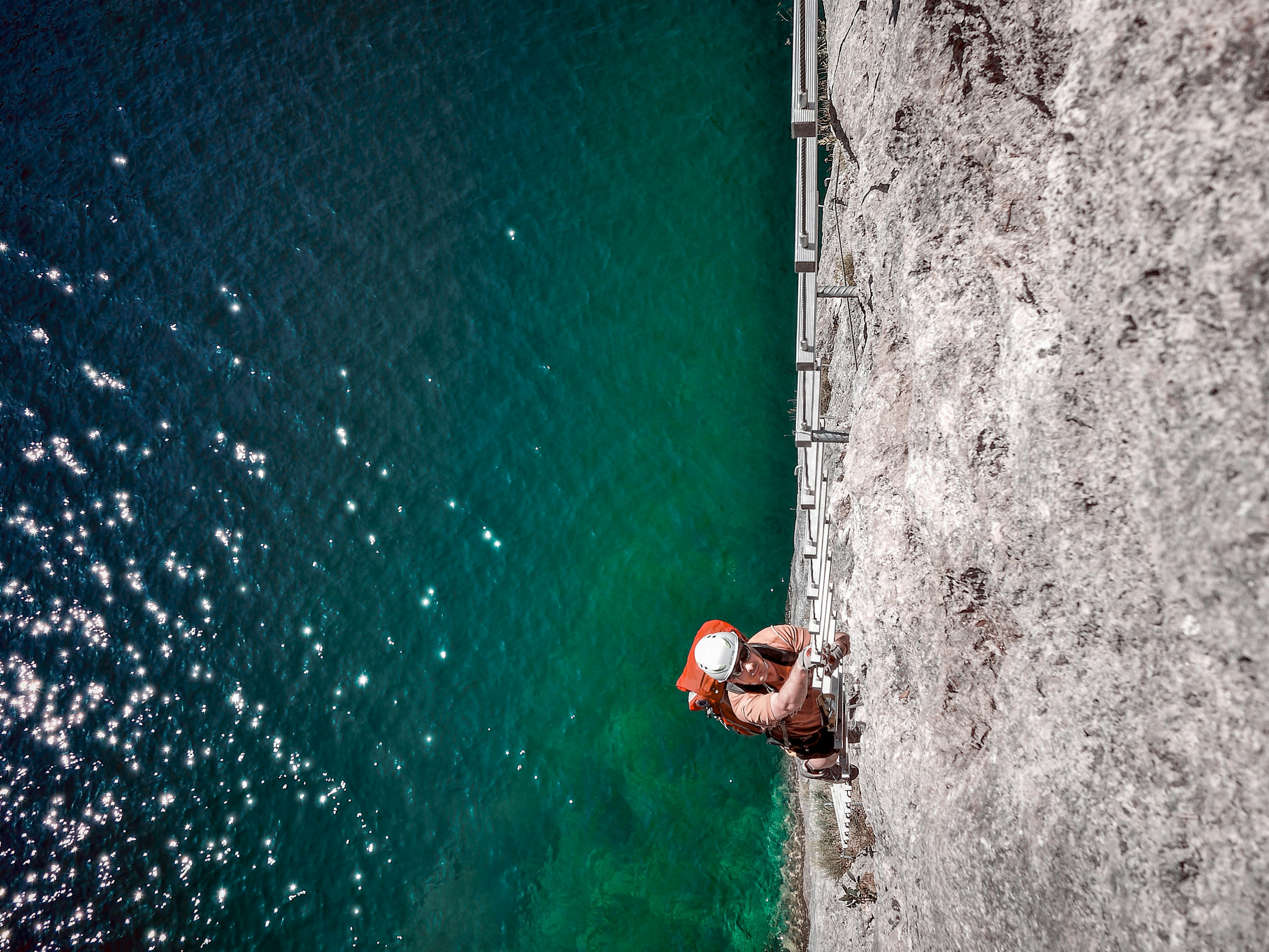 man climbing on ladder above sea level